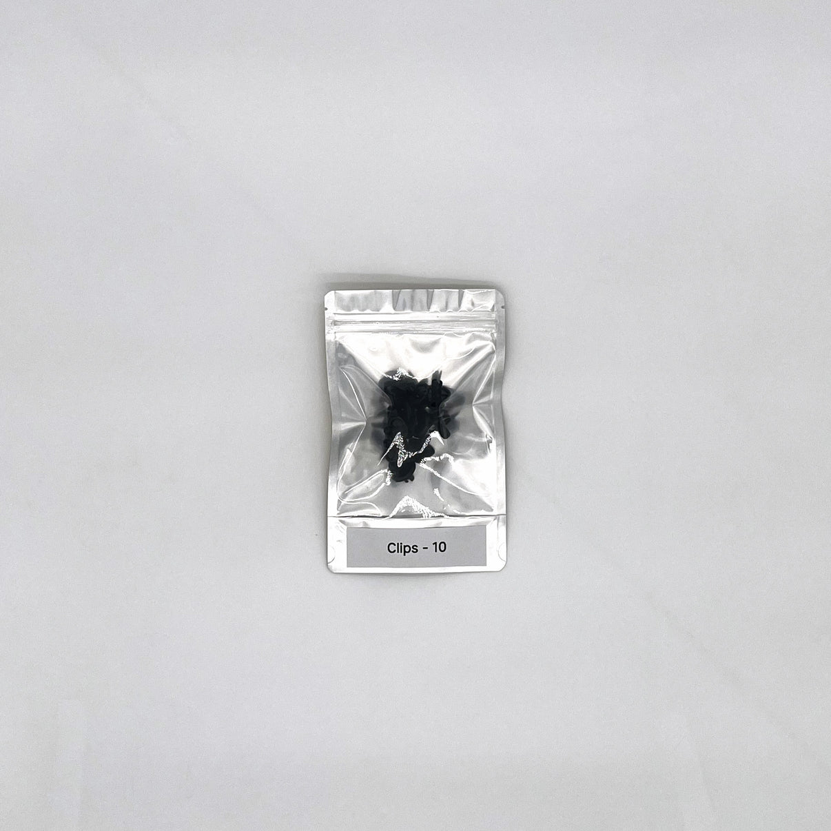 Silver packaging with 10 black clips on a gray background